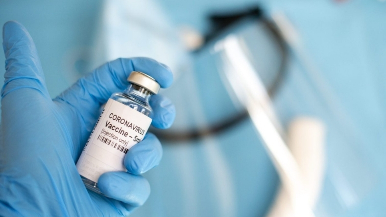 Close-up of a coronavirus vaccine vial in a blue-gloved hand