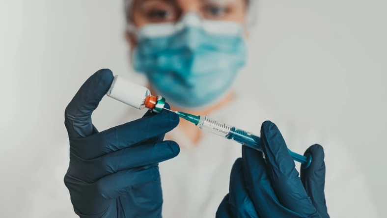 Gloved researcher drawing liquid into syringe in lab
